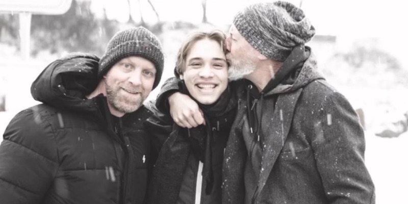 Thias, Charlante und Caspar Stitz Arm in Arm im Schneegestöber, einer gibt einem anderen einen Kuss auf die Wange.