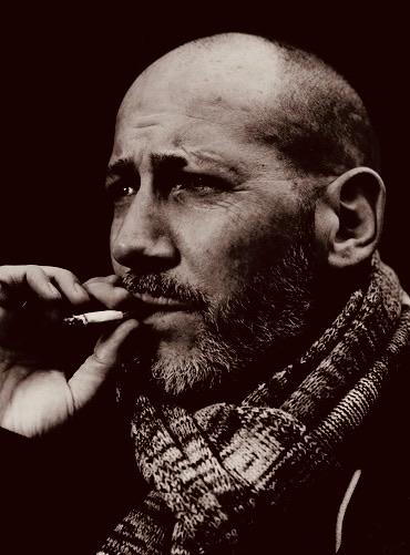 Sepia-Portrait: Thias mit Strickschal und Zigarette, der Blick geht zur Seite.